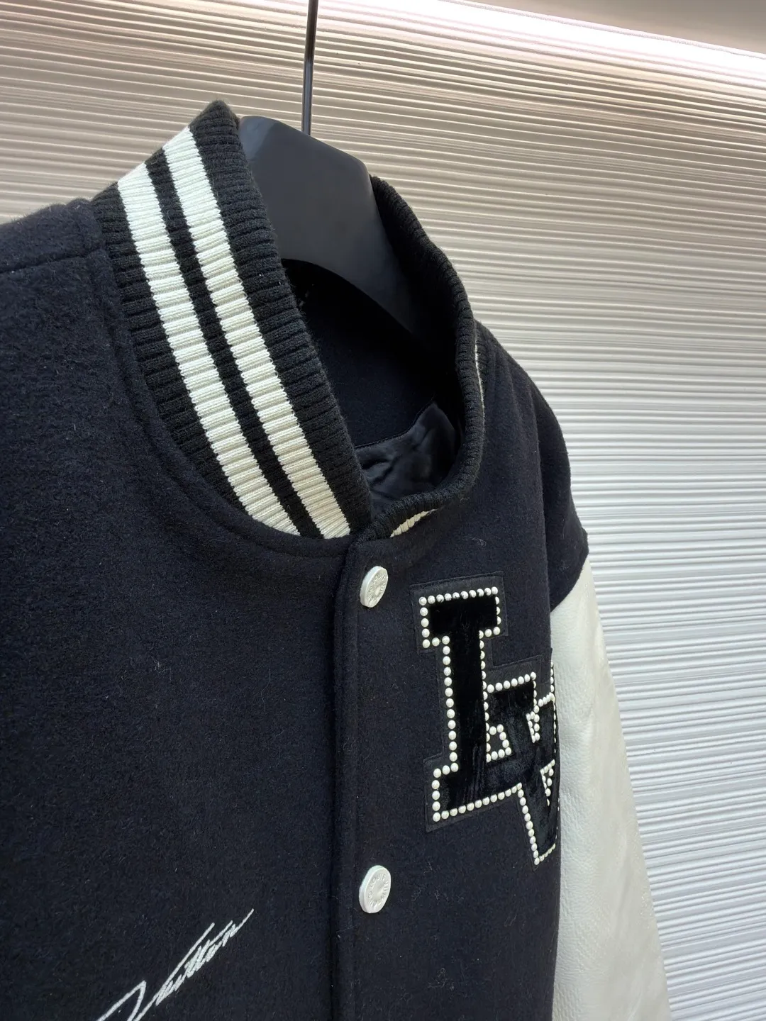 LOUIS VUITTON checkerboard embossed genuine leather and wool baseball jersey ●Original version: 51000 purchased and developed ●Item number: 1680926-i15 ●Fabric: genuine leather wool fabric ●Technology: embroidery ●Version: fitted version ●Weight: about 1770 grams ●Size: 44-46-48-50 ●Description: The fabric is made of 80% wool, with a weight of 750g. It is made of newly sheared wool and is dyed in reactive black in the vat. The colored cloth is bristle process. After brushing 5 times and washing 6 times, the fluffy surface fluff is trimmed flat, and the surface of the fabric appears fluffy. It has a hollow three-dimensional fluffy effect. You can feel the elasticity of the fabric when you touch and press it with your hands. The newly sheared wool yarn is long-fiber and is not easy to pill after shearing. The front and back panels are embroidered with Tajima embroidery machines imported from Japan. The nylon material is super matte and the tatami stitch method is multi-layered. Overlapping thread embroidery, the front chapter is made of viscose yarn, three-dimensional toothbrush embroidery, the mold is opened to determine the pile height and the suede is smoothed by hand, using acrylic round bubble beads, the surface of the bubble beads is sprayed three times, the base paint is latex paint, and the middle layer is sprayed with pearls Pearl white paint, the outer layer is sprayed with translucent glossy paint, the translucent bright white effect is completely comparable to that of mother-of-pearl. There are a total of 154 beads in the chapter. Each bead is dusted and positioned to ensure that it is flush with the edge of the chapter. The visual effect is not obtrusive. The two sleeves are made of water Made of dyed cowhide. Compared with spray-painted cowhide, there is nothing attached to the surface of water-dyed cowhide. Pure water-based dyes are continuously stirred in the tank to naturally color. During the period, samples are taken to compare the color of the Y-version sleeves according to the degree of coloring. When the colors are basically the same, they can be washed and dried naturally to produce the finished product. The thickness of the finished leather is 12mm. The embossing is made of a large-size aviation aluminum plate material mold. All the flowers are pressed according to the code positioning. An electric hydraulic control system is used, and the constant temperature and timing are automatically operated. The small sleeve logo is embossed separately from the small mold. It is pressed by electromagnetic pulse pressure and heating. After the sleeves are cut and embossed, the leather base is all shoveled to a thickness of 8mm. The leather thickness is reduced and the hand feels softer and closer to the body. The diamond-shaped plaid embossing on the surface causes an anti-skin phenomenon due to the thinning of the leather base. The pattern will naturally increase from the deep base state. Lightened, the diamond check pattern and the leather pebbles form a visually invisible effect. It is matched with cupro + cotton blended lining, the ribs are made of combed cotton yarn, and the horizontal loom imported from Taiwan has inter-color jacquard. It is matched with a custom-made molded aluminum alloy material with a logo spray-painted four-button buckle.
